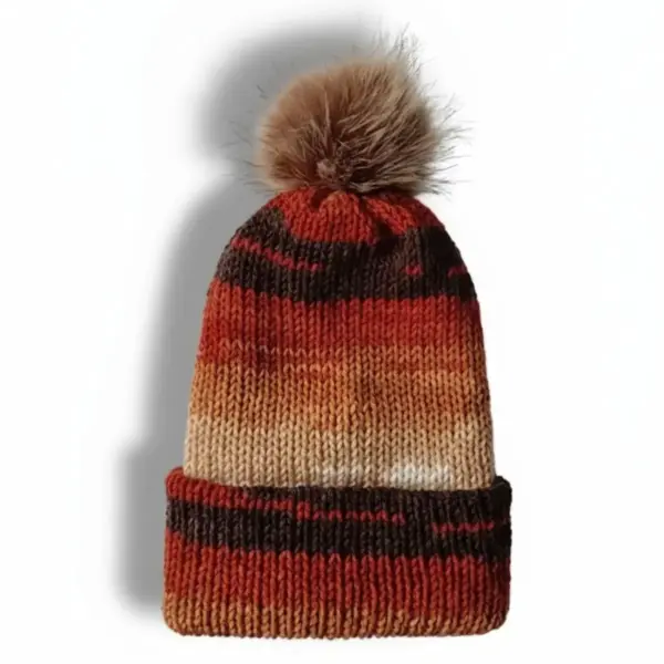Knitted beanie in autumn colors with a brown faux fur pom-pom on a white background