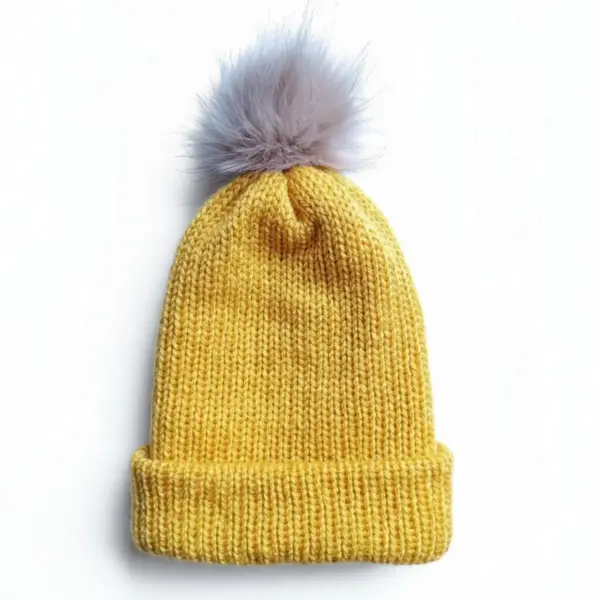 golden yellow knitted beanie with fluffy light grey pom pom on white background