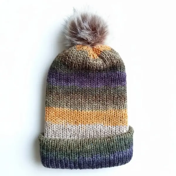 Striped knit hat in earthy colors with brown faux fur pom-pom on a white background.