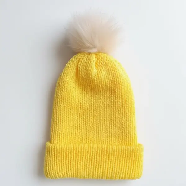 yellow knitted beanie with light beige pom pom on white background